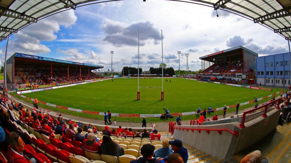 An image of the stadium from inside the grounds, stands can be seen with fans sat around the pitch.