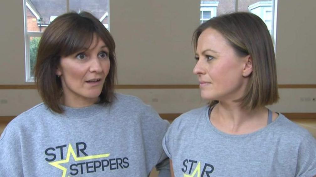 Hannah Gunning and Anna Judge, the directors of Star Steppers performance group, standing side by side and wearing grey branded t shirts.