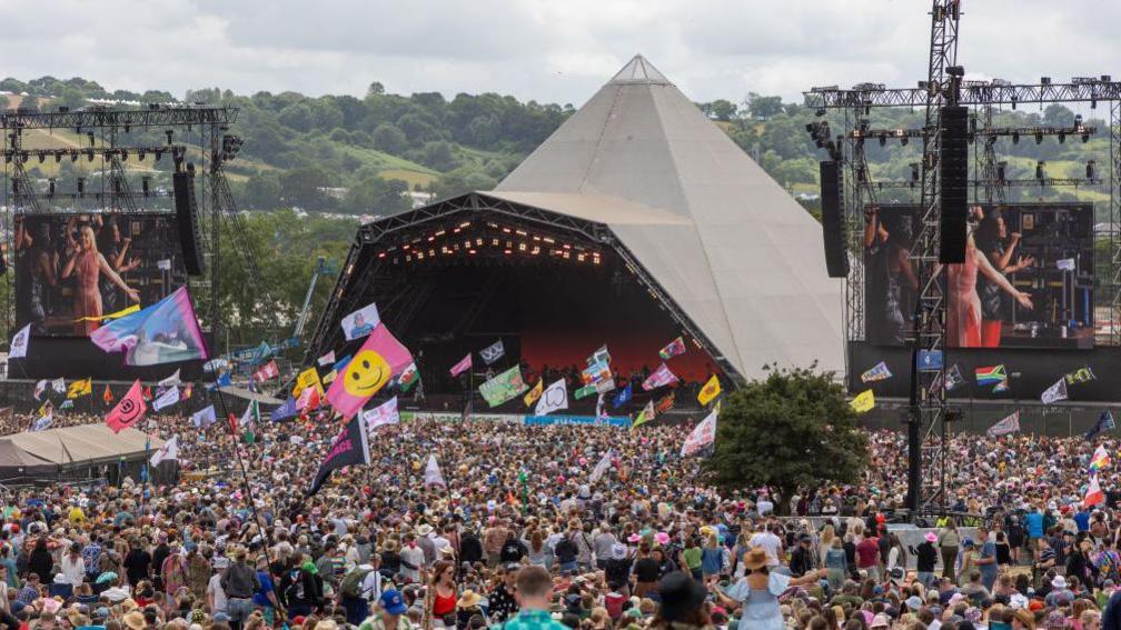 The pyramid stage at Glastonbury Festival. Thousands of people gather around the iconic tent.
