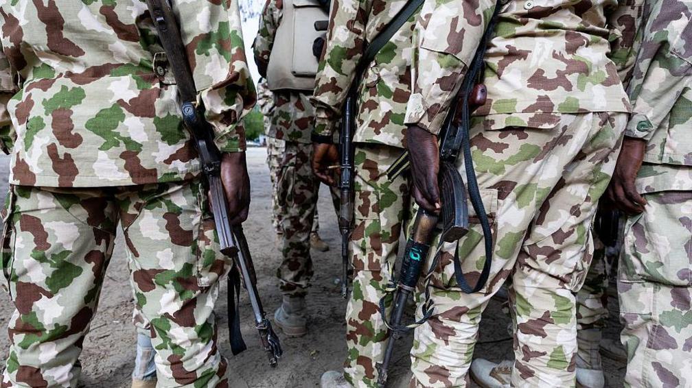 Nigerian soldiers, in camouflage uniform, from the Multinational Joint Task Force (MNJTF) hold Kalashnikovs at the MNJTF military base