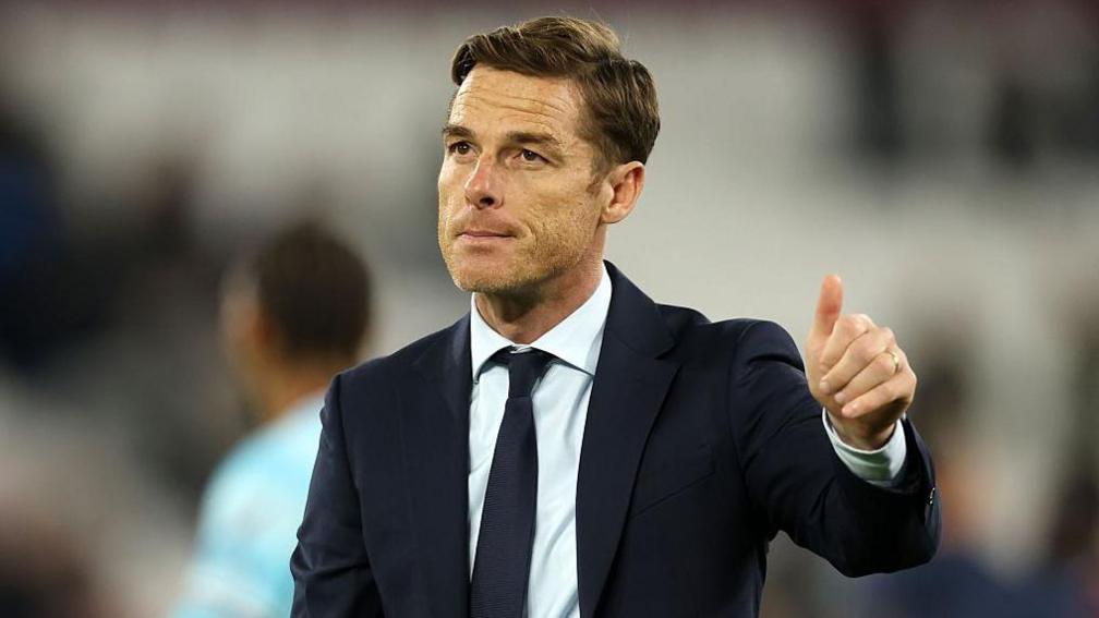 Scott Parker wearing a navy blue suit and tie with a white shirt