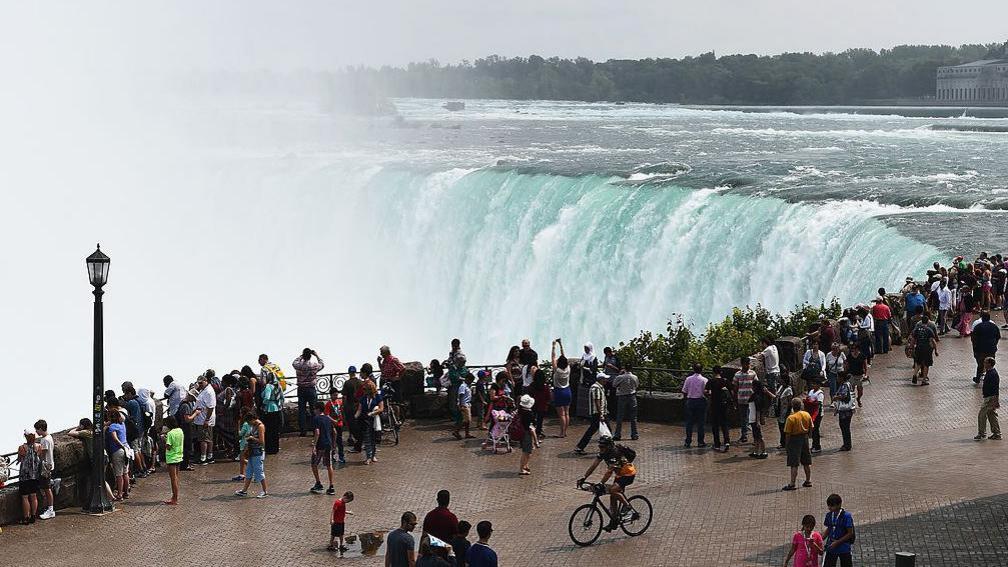 People at Niagara Falls, which is shared by Canada and the US