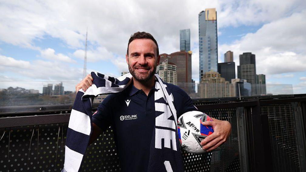 Juan Mata wearing a Melbourne Victory scarf after signing for the club