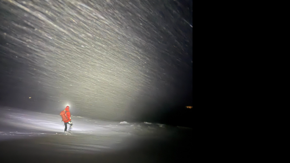 Neach-teasairginn nam beann a-muigh air iomairt cobhair air an oidhche a' coiseachd san t-sneachd agus gèile ann