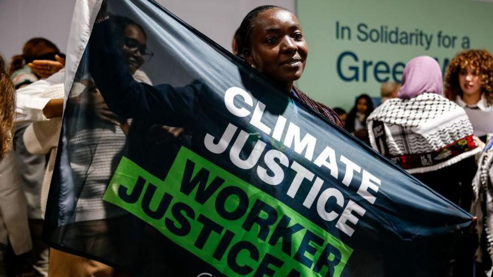 A protestor at COP29 displays a banner calling for climate justice