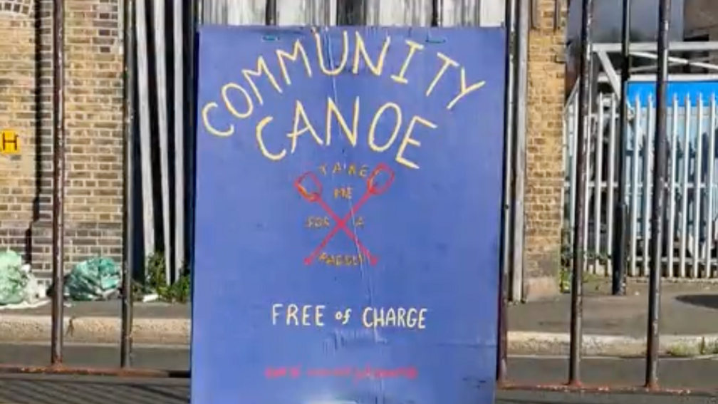 A blue sign reads 'Community Canoe Free of Charge' with a link to book the canoe on it.