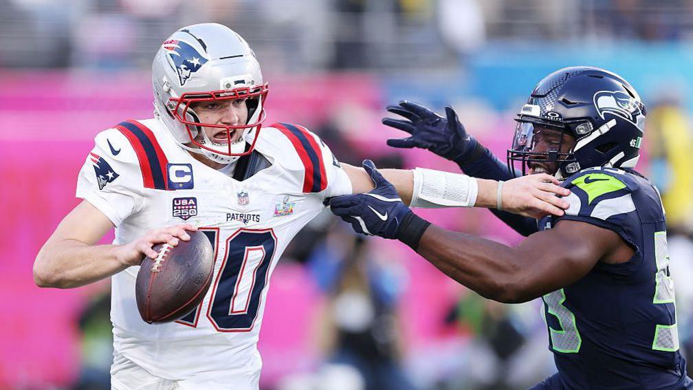 Drake Maye tries to escape from a tackle