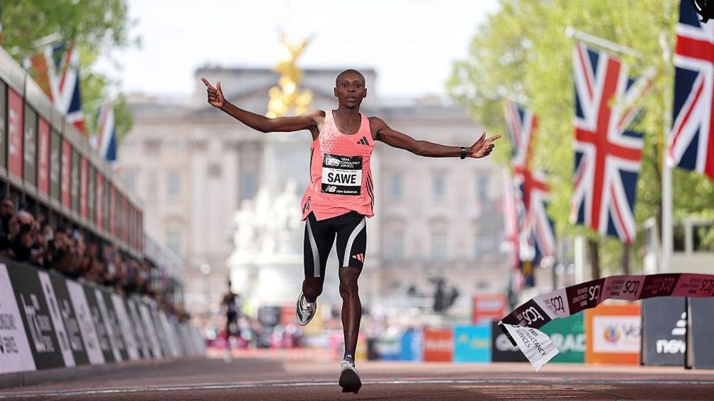Sabastian Sawe holds up the Adidas supershoe which he wore in breaking the marathon world record in London
