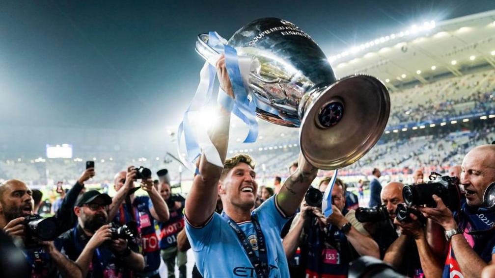 John Stones holds up the Champions League trophy