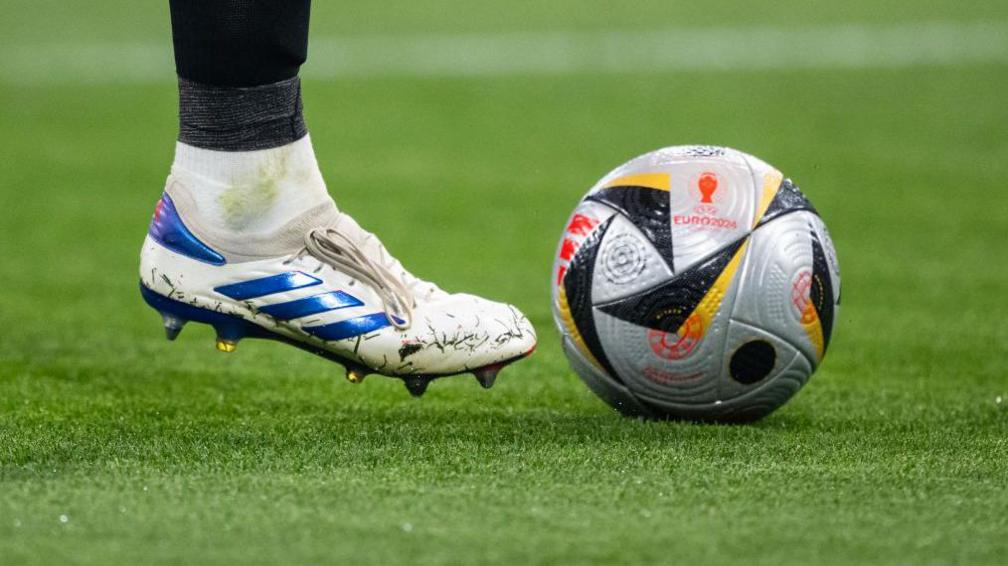 Football boot next to silver ball