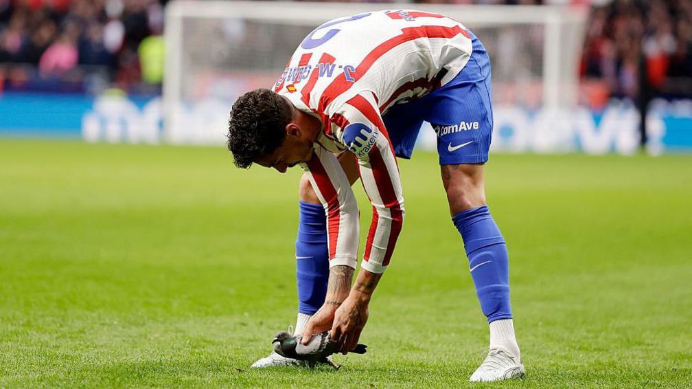 Jose Gimenez of Atletico Madrid takes a pigeon of the pitch during the La Liga match between Atletico de Madrid and Real Sociedad 