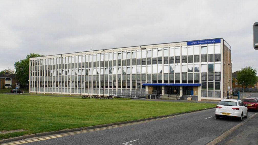 The front of Guild House, a three-storey, rectangular-shaped building with rows and rows of windows and the Anglia Ruskin University sign on it