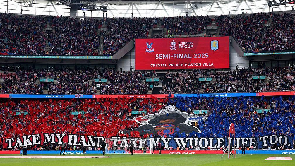 Crystal Palace's tifo prior to their FA Cup semi-final against Aston Villa. It reads "Take my hand, take my whole life too." and is in front of a picture of a child's head in front of the FA Cup and fans holding up red and blue banners.