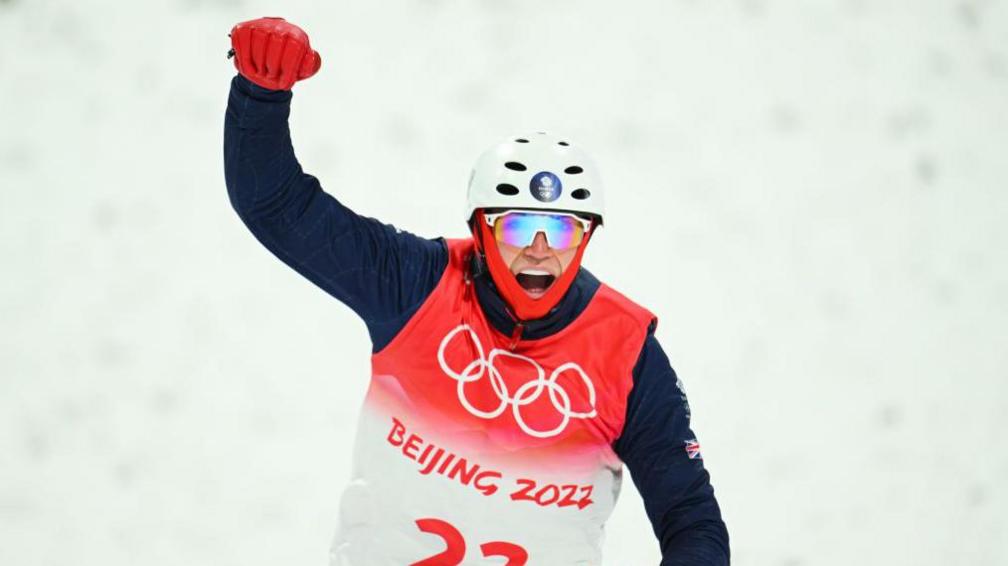 Lloyd Wallace holds his arm in the air after landing a jump in the 2022 Beijing Games 