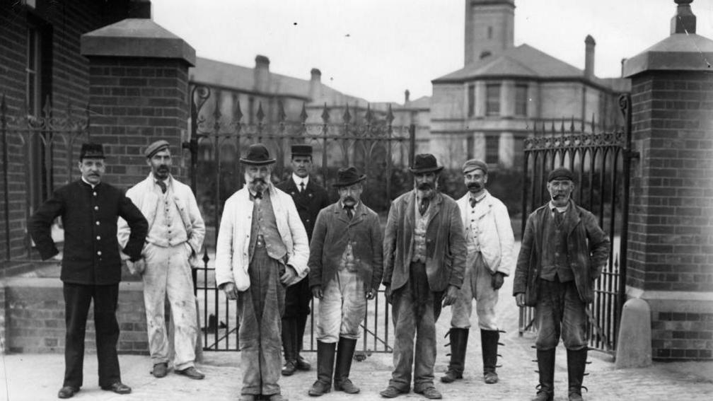 A black and white picture showing a group of men stand outside the Horton Asylum