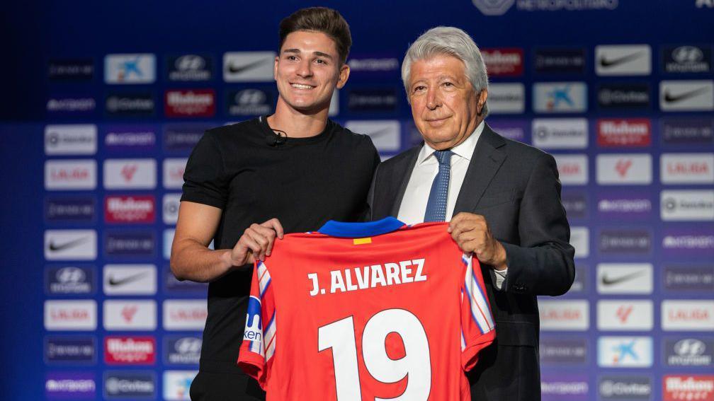 Julian Alvarez holds up a shirt at his unveiling for Atletico Madrid