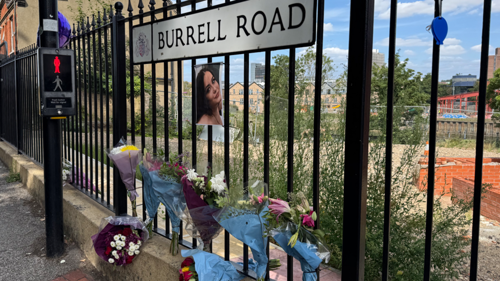 Bouquets of flowers attached to black fencing in Burrell Road, Ipswich. A photo of Courtney Mitchell is also attached. 
