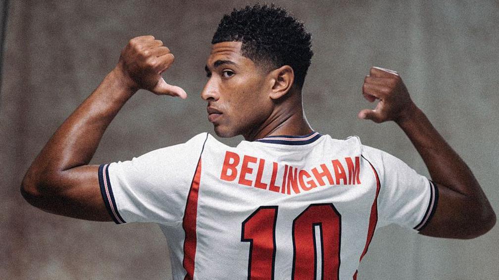 Jude Bellingham points to the number 10 on the back on his England shirt in a pre-World Cup publicity photograph