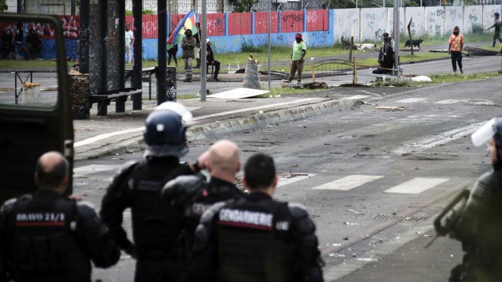 French gendarmes stand guard near independantists at the entrance of the Riviere Salee disctrict, in Noumea, France's Pacific territory of New Caledonia, on May 29, 2024