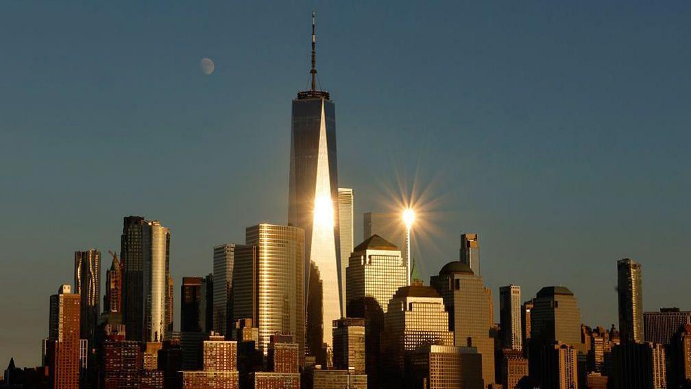 A crescent moon rises behind the skyline of lower Manhattan and light reflects off the One World Trade Center as the sun sets in New York City on 3 September, 2025, as seen from Jersey City, New Jersey.