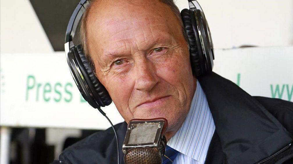 Edwin Overland wearing headphones and talking into a lip mic at a sports ground