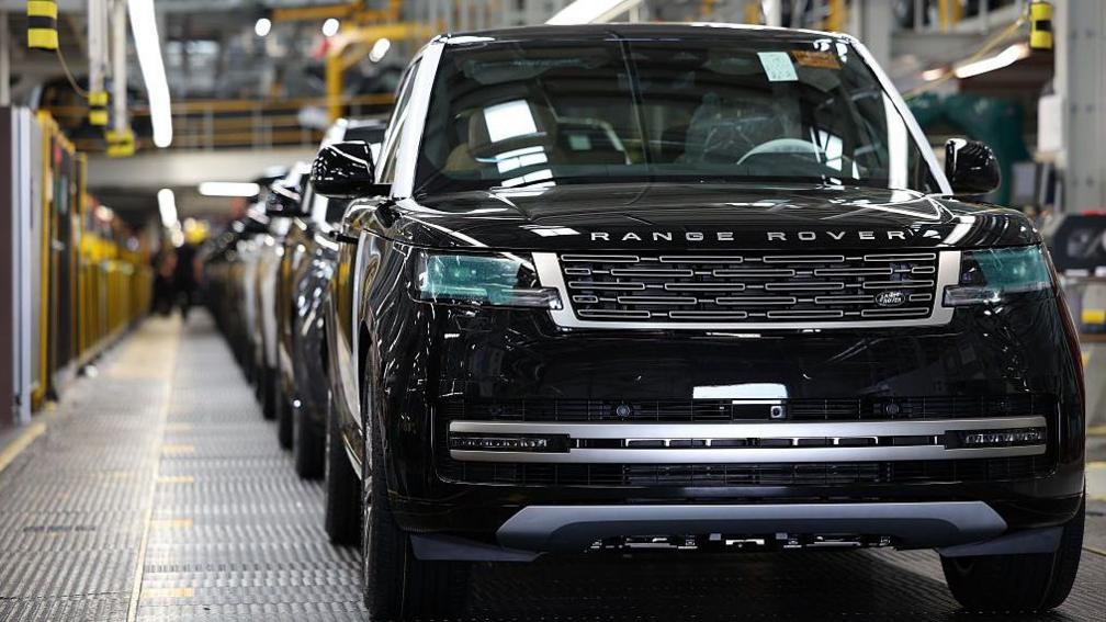 A row of black Range Rover cars on a production line