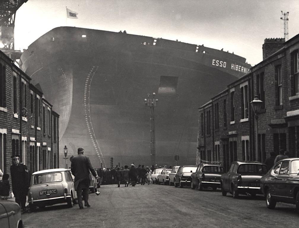 Photo of huge ship, Esso Hibernia at the end of street showing houses, cars and people