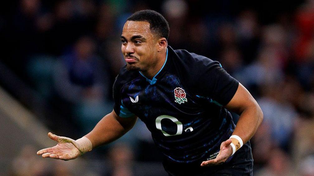 Max Ojomoh playing for England with his arms by his side in an expression of mock bewilderment