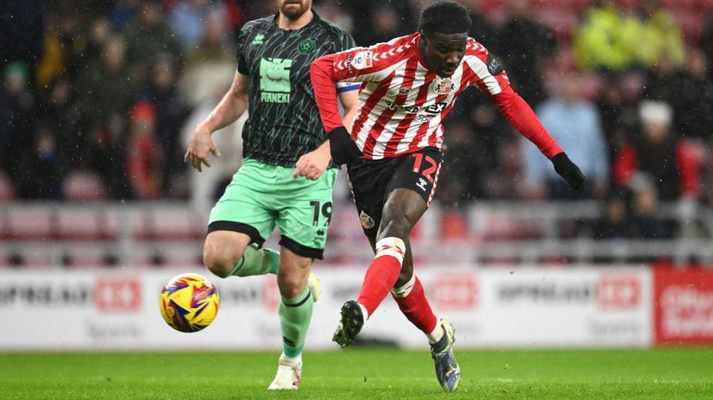 Eliezer Mayenda shoots and scores for Sunderland against Sheffield United, while being pursued by the Blades' Jack Robinson