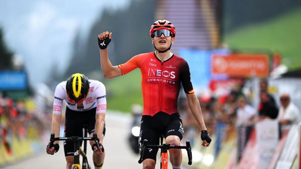 INEOS Grenadiers' Carlos Rodriguez celebrates crossing the line by raising his fist at the end of a stage during the 2024 Tour de France.