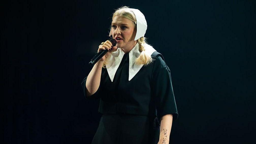 Rebecca Lucy Taylor of Self Esteem performs at Big Weekend, wearing a black outfit with a white head covering.