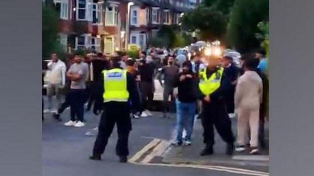 Police standing in front of a large crowd in the North Lodge Park area of Darlington