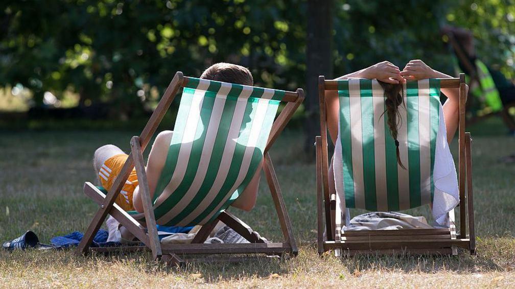 image of two people relaxing on deck chairs from behind