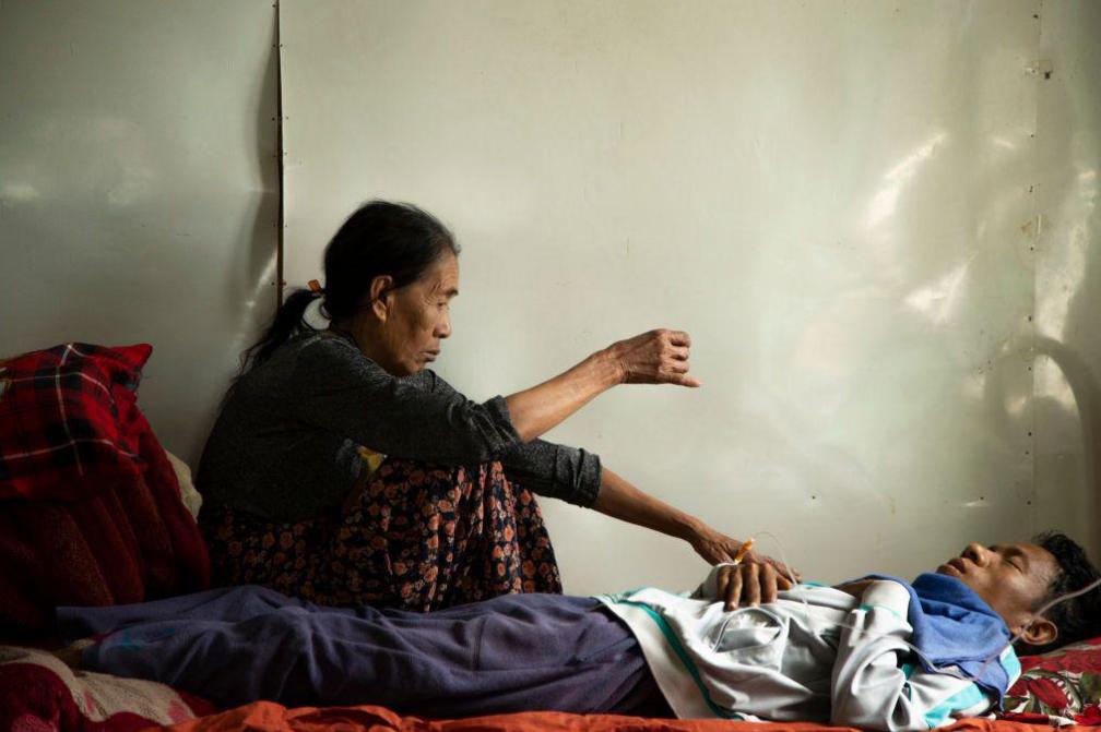 A woman sits beside Malsawm Puia, 28, who suffers from blood cancer, in Kale township on the India-Myanmar border, on April 17, 2024. Puia was receiving treatment in Mizoram, India.
