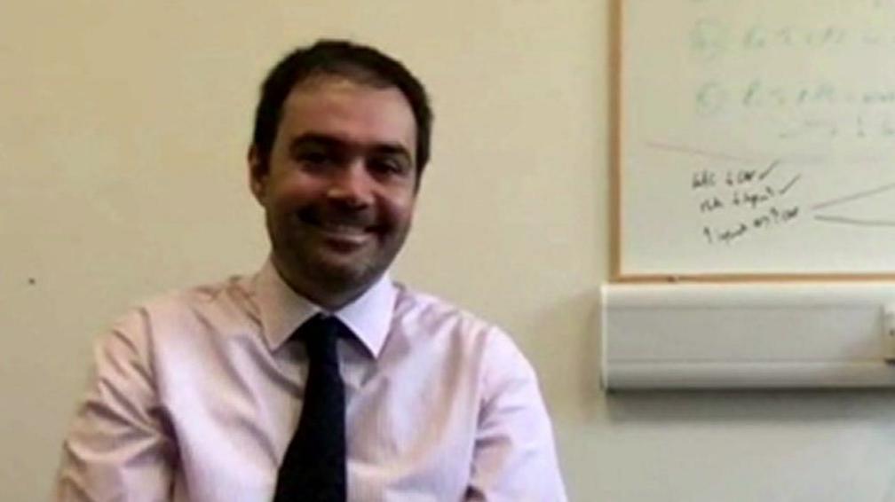 Fabrizio De Rita smiling during a zoom interview. He is wearing a shirt and tie.