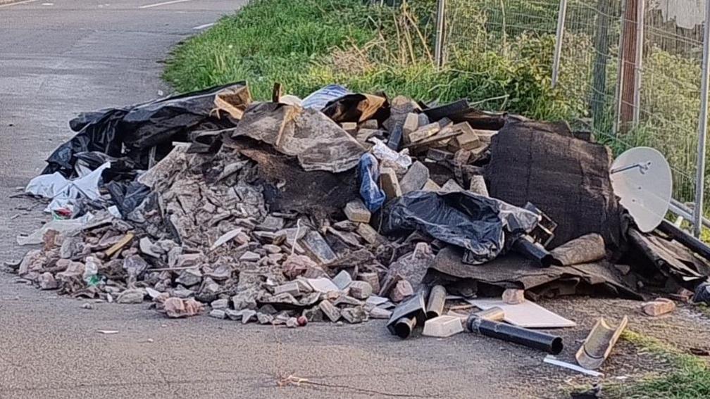 Rubbish including bricks dumped on the side of the road 