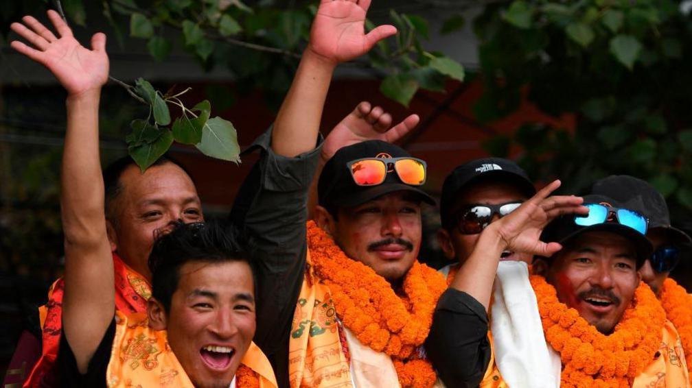 Nepali mountaineer Nirmal Purja (C) waves with teammate Mingma David Sherpa (R) after arriving at Tribhuvan airport in Nepal's capital Kathmandu on October 30, 2019.