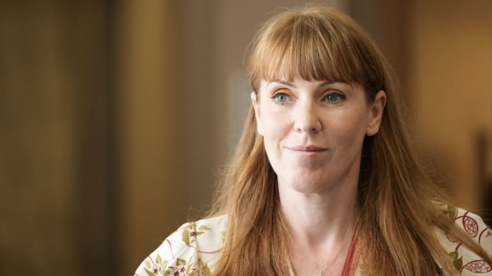 A woman with long ginger hair smiles at the camera.