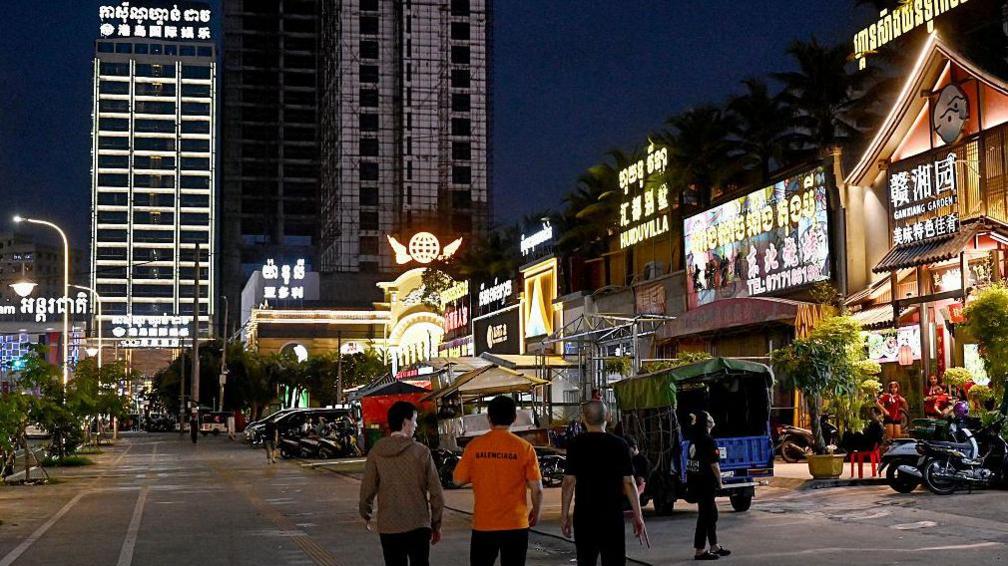 This photo taken on April 8, 2025 shows people walking past Chinese restaurants and shops in Sihanoukville. Once a collection of sleepy fishing villages, vast Chinese investments have transformed the Cambodia's Sihanoukville into a half-finished gambling resort with signs everywhere in Mandarin.