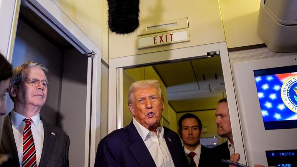 Donald Trump speaks to reporters aboard Air Force One
