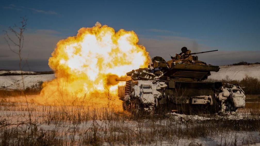 Një shpërthim i madh flakësh të bardha dhe portokalli që vjen nga një tank ukrainas, ndërsa qëllon drejt pozicioneve ruse në një peizazh me dëborë në rajonin e Donetskut në janar 2024.