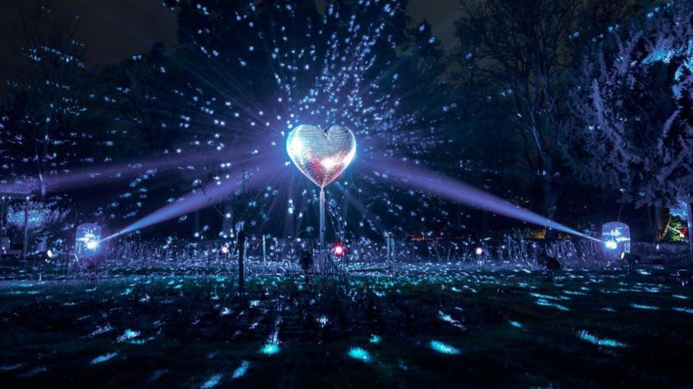 A heart-shaped disco ball in the dark with light reflecting off it.