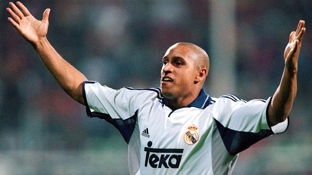 Roberto Carlos wearing a white Real Madrid shirt holds out his arms