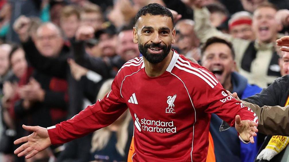 Mohamed Salah celebrates scoring with his arms out wide in front of the Liverpool fans