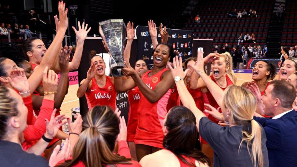 England's Liv Tchine, surrounded by team-mates, lifts the Taini Jamison Series trophy after the Roses beat New Zealand in 2024