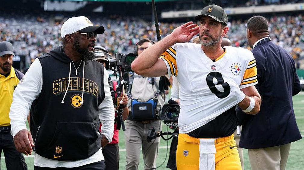 Aaron Rodgers, alongside Pittsburgh Steelers head coach Mike Tomlin, cups his hand to his ear