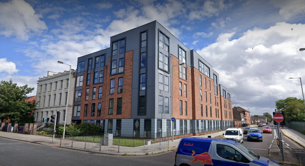 Parliament Place, a development in Liverpool. It stands on the corner of two roads and is clad in grey cladding and brick-effect cladding. It is five storeys tall. 