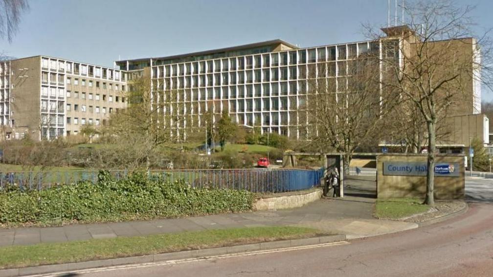 Durham County Council HQ. A slightly brutalist, roughly eight story building. Made up of many windows and concrete. It has the look of a 1960s polytechnic.