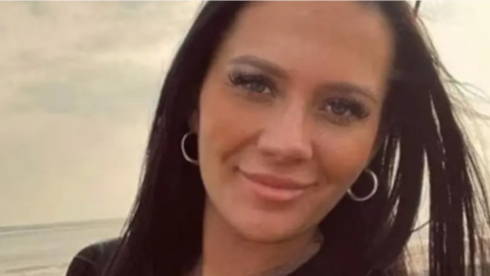 Head and shoulders image of Kiena Dawes on a beach, she has long straight dark hair and is smiling