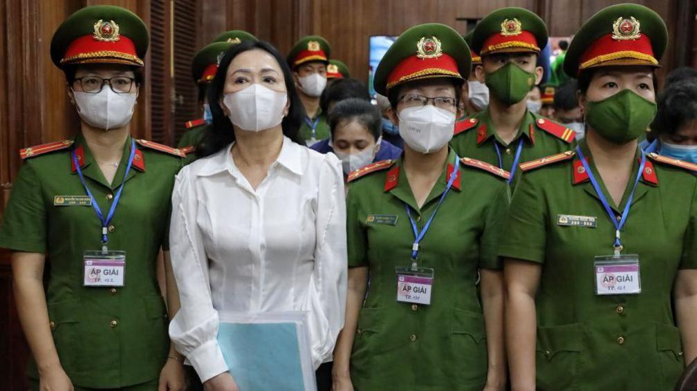 Truong My Lan, second left, in a white shirt arrives in court in March 2024. 